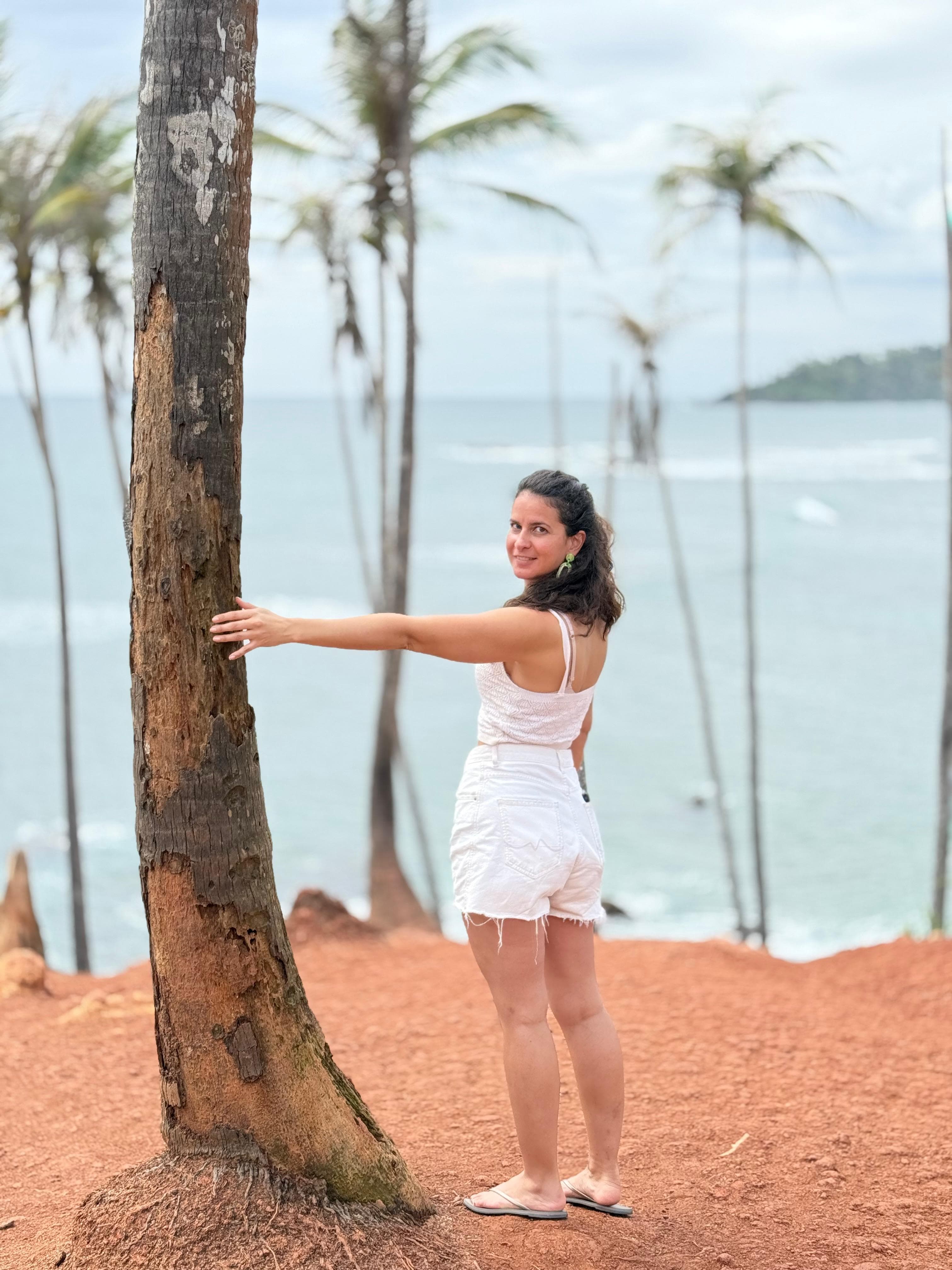 Woman by a palm tree on the red-dirt coast