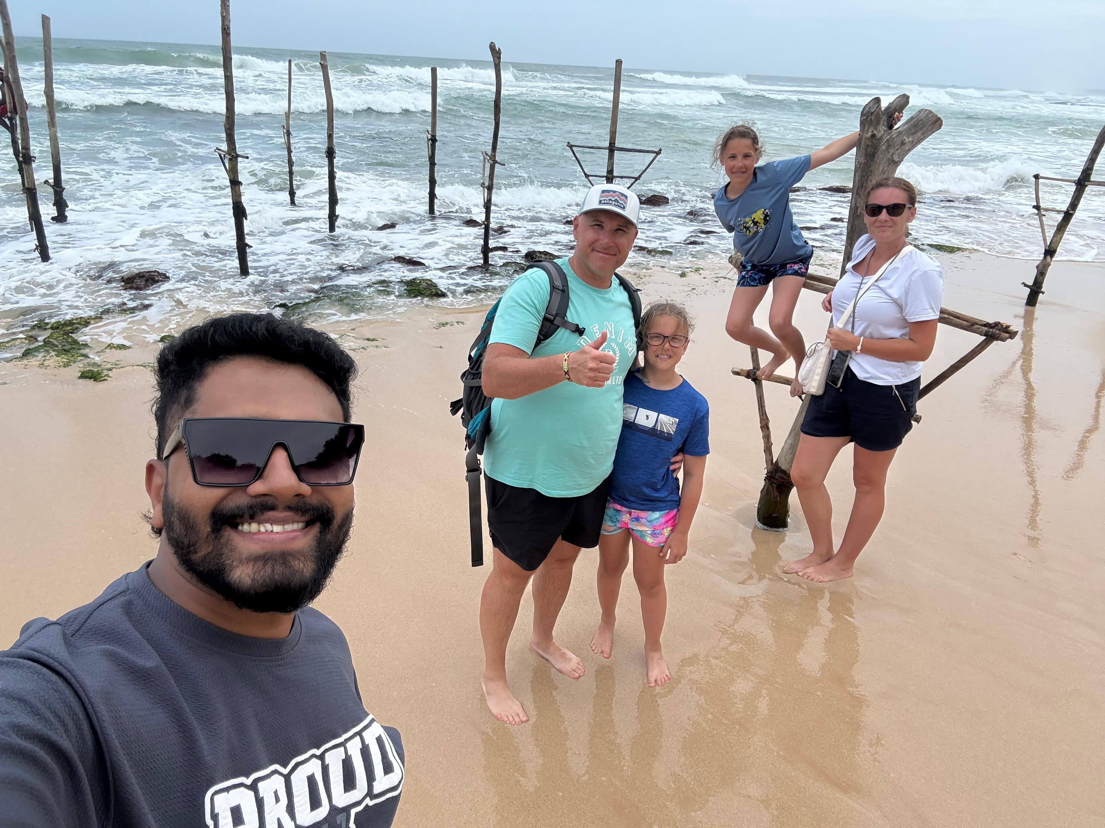 Family by the stilt fishing posts on the beach