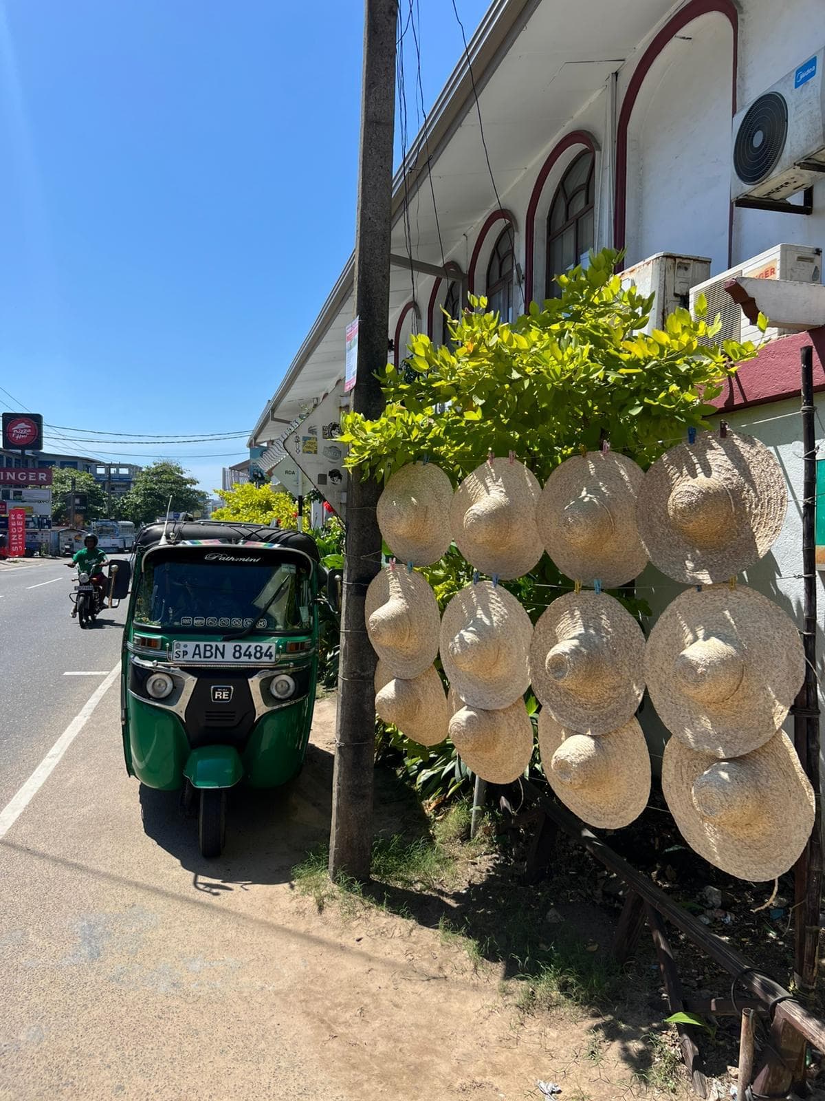 Tuk-tuk on the street beside a straw hats stall