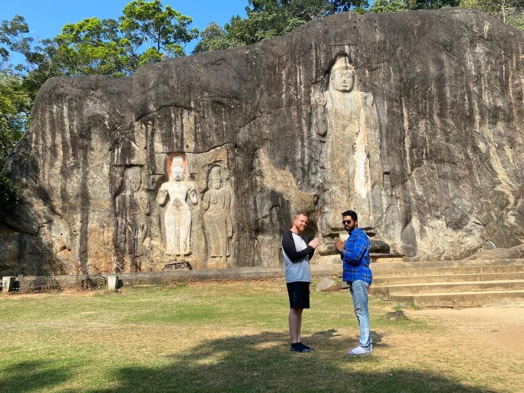 Men beside ancient Buddha rock carvings