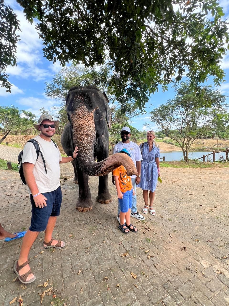 Family with an elephant beside a lakeside tree