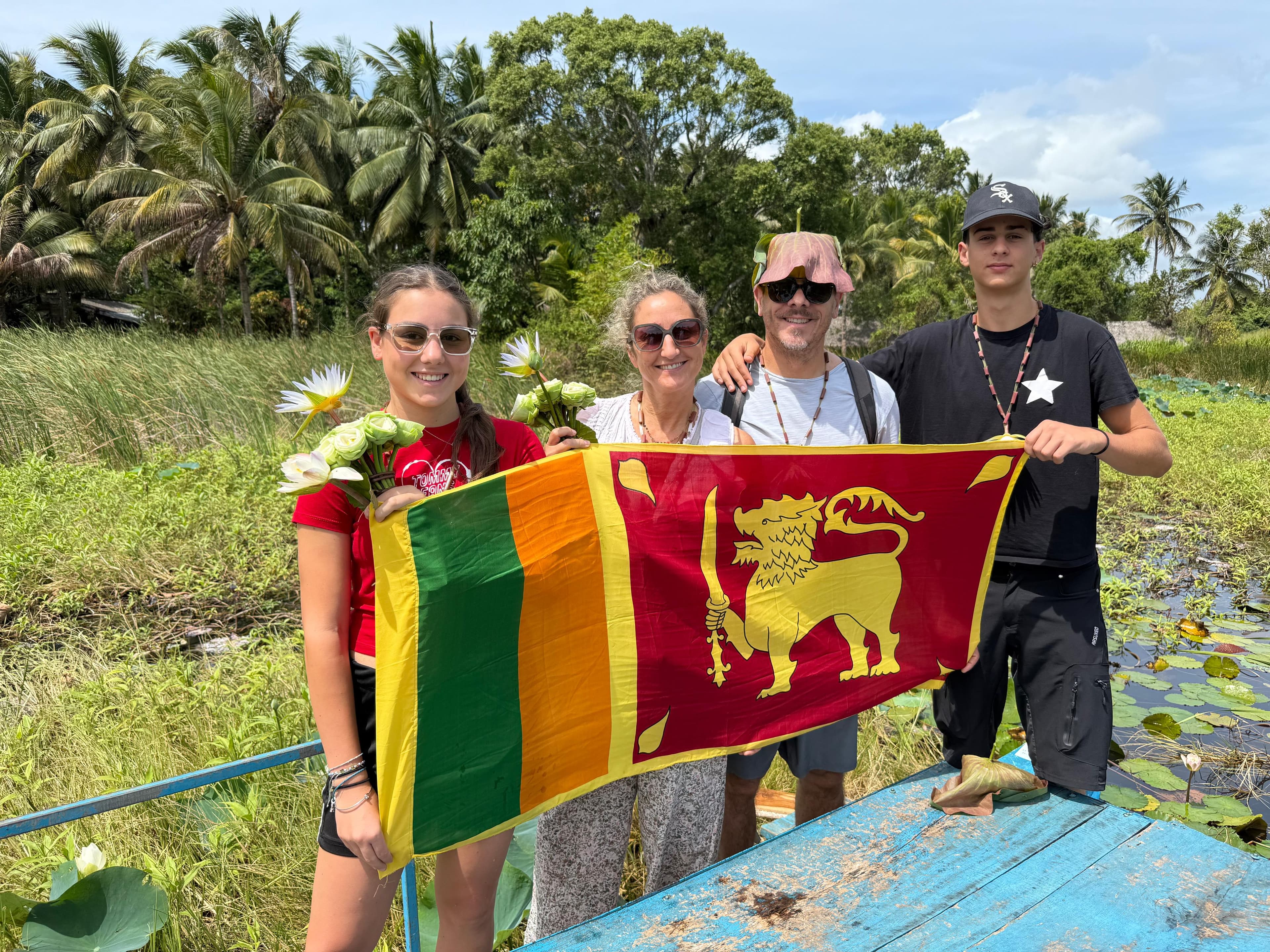 Family with the flag among lotus flowers on a boat