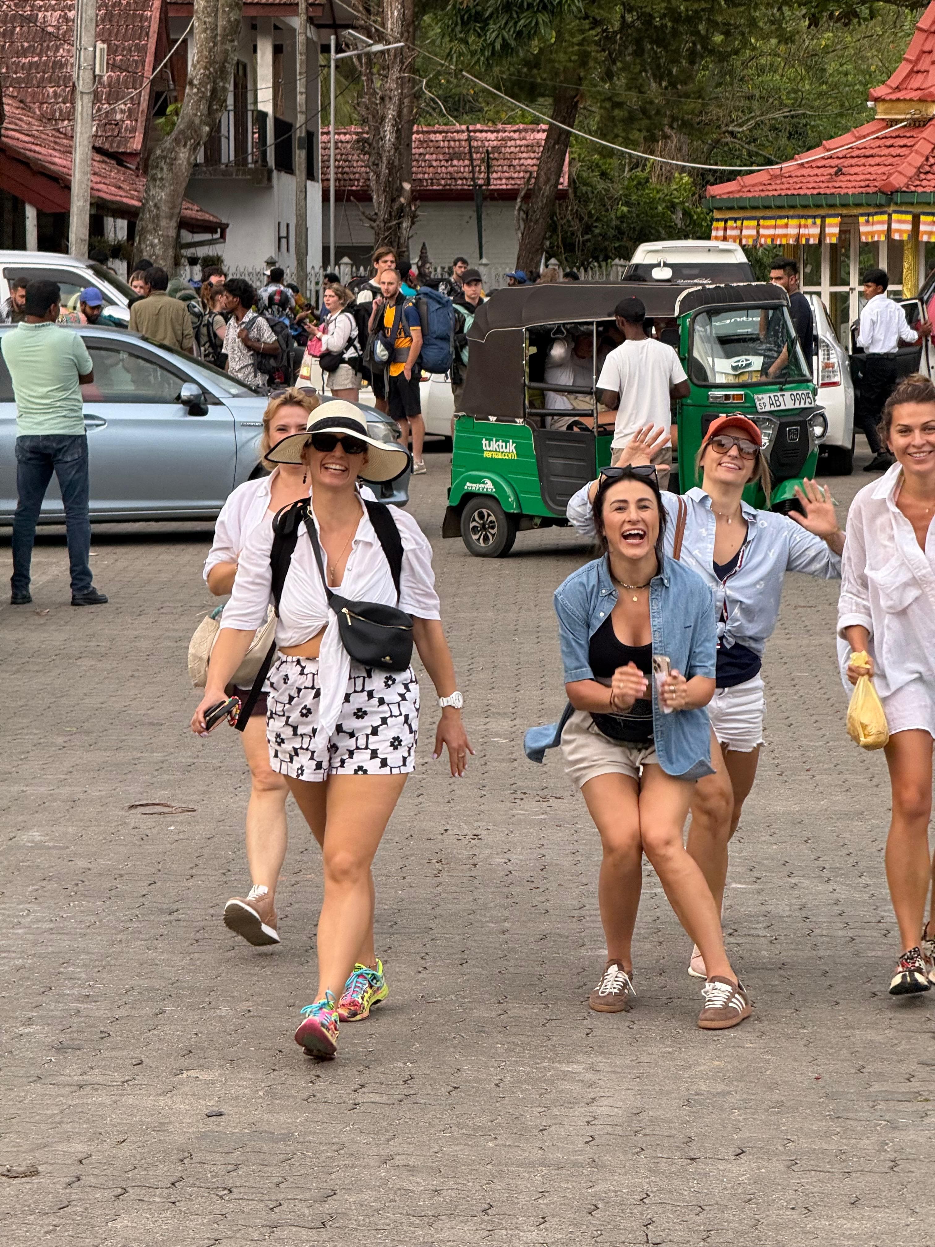 Group of women on the street near a tuk-tuk and temple