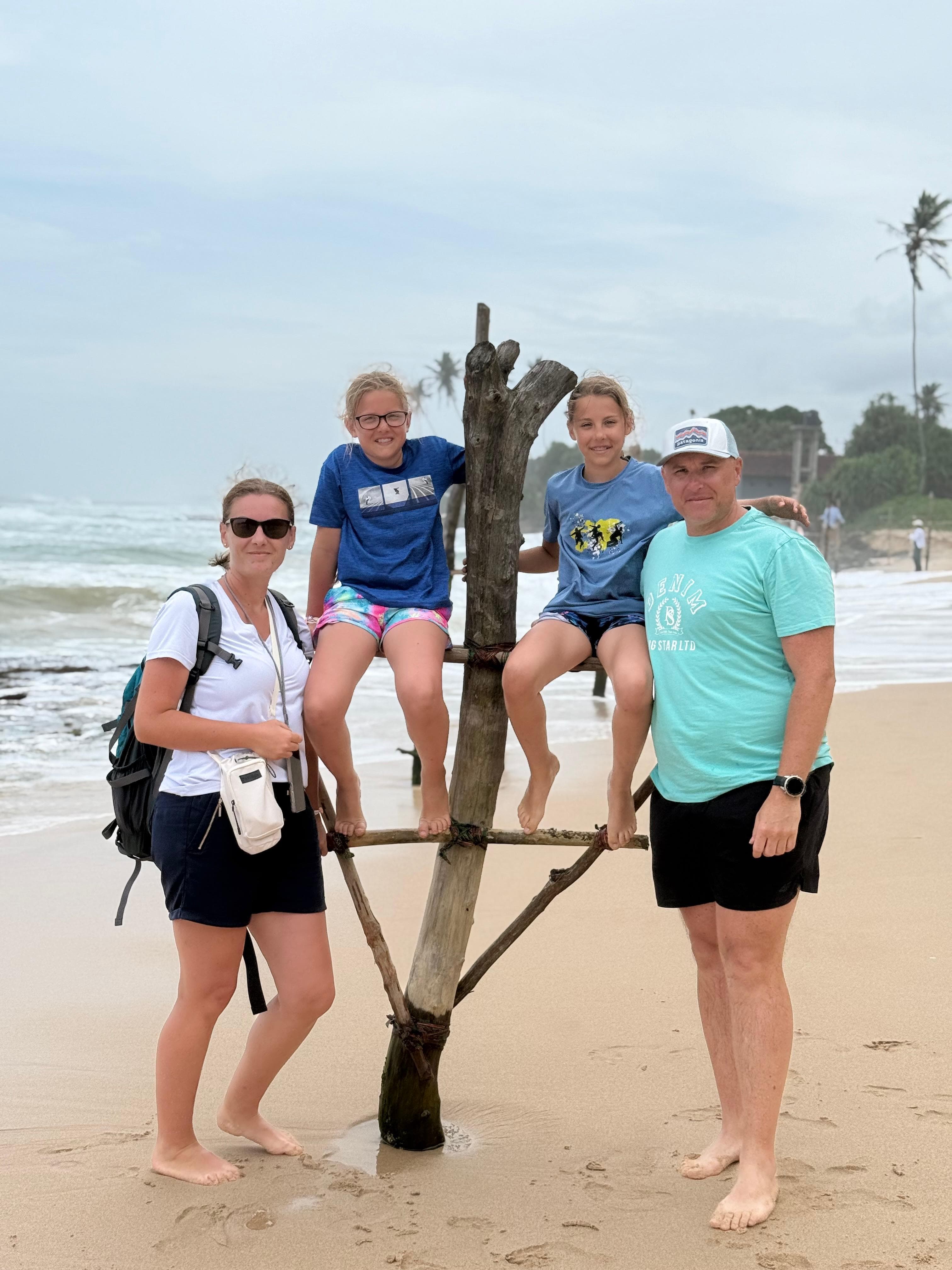 Family posing with driftwood on the beach