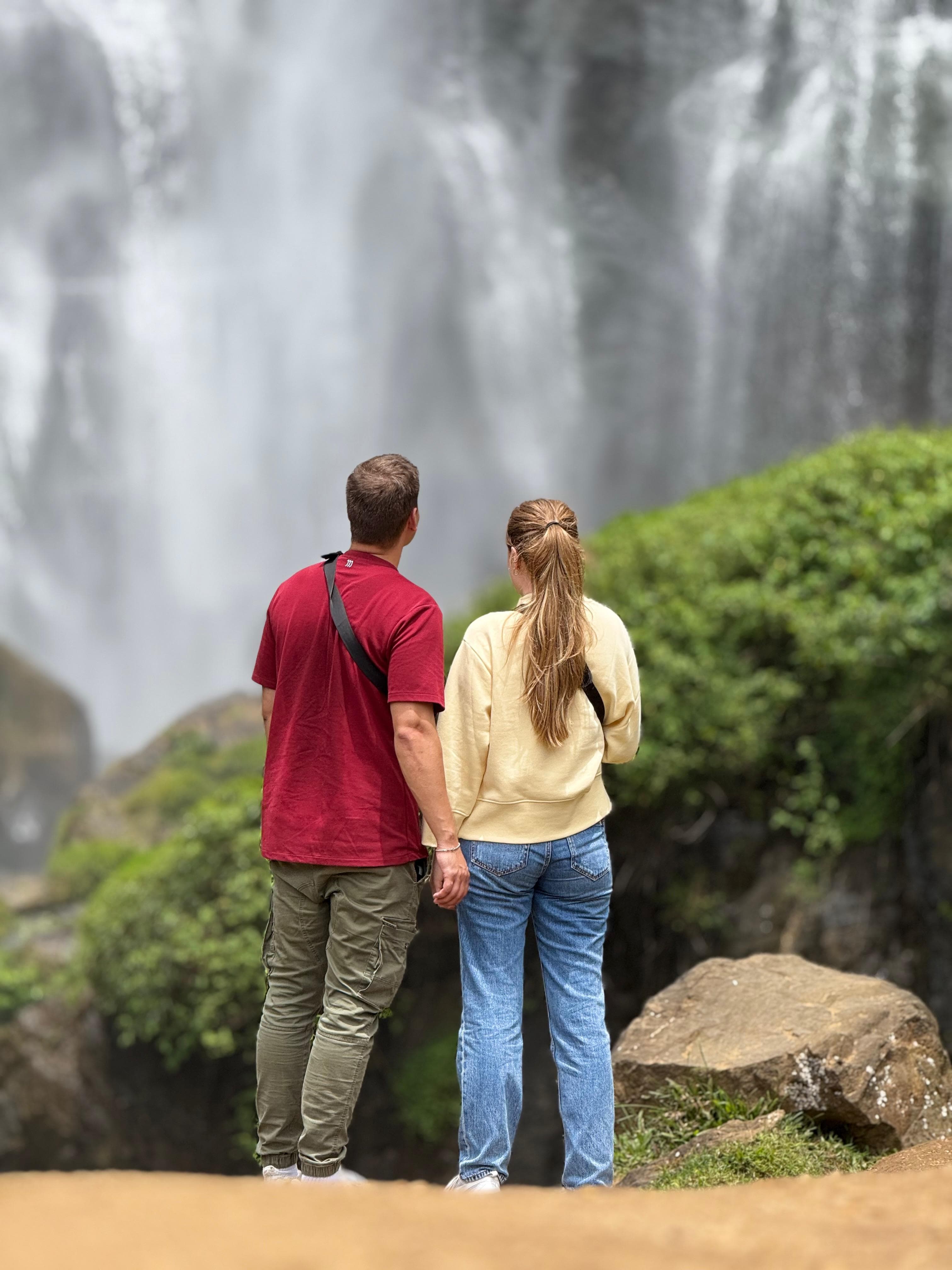 Couple viewed from behind at a waterfall