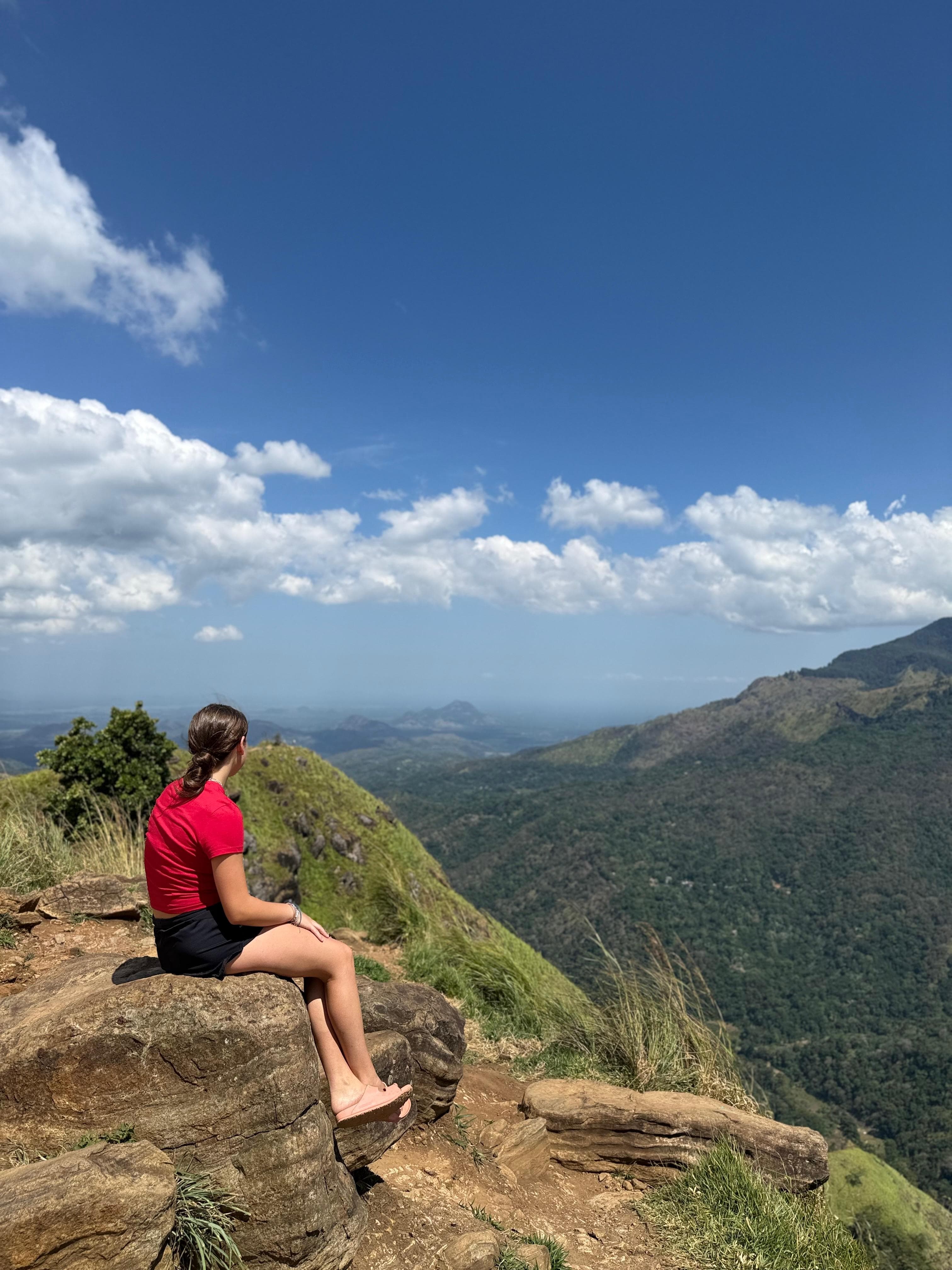 Woman on a rock ledge with a mountain panorama