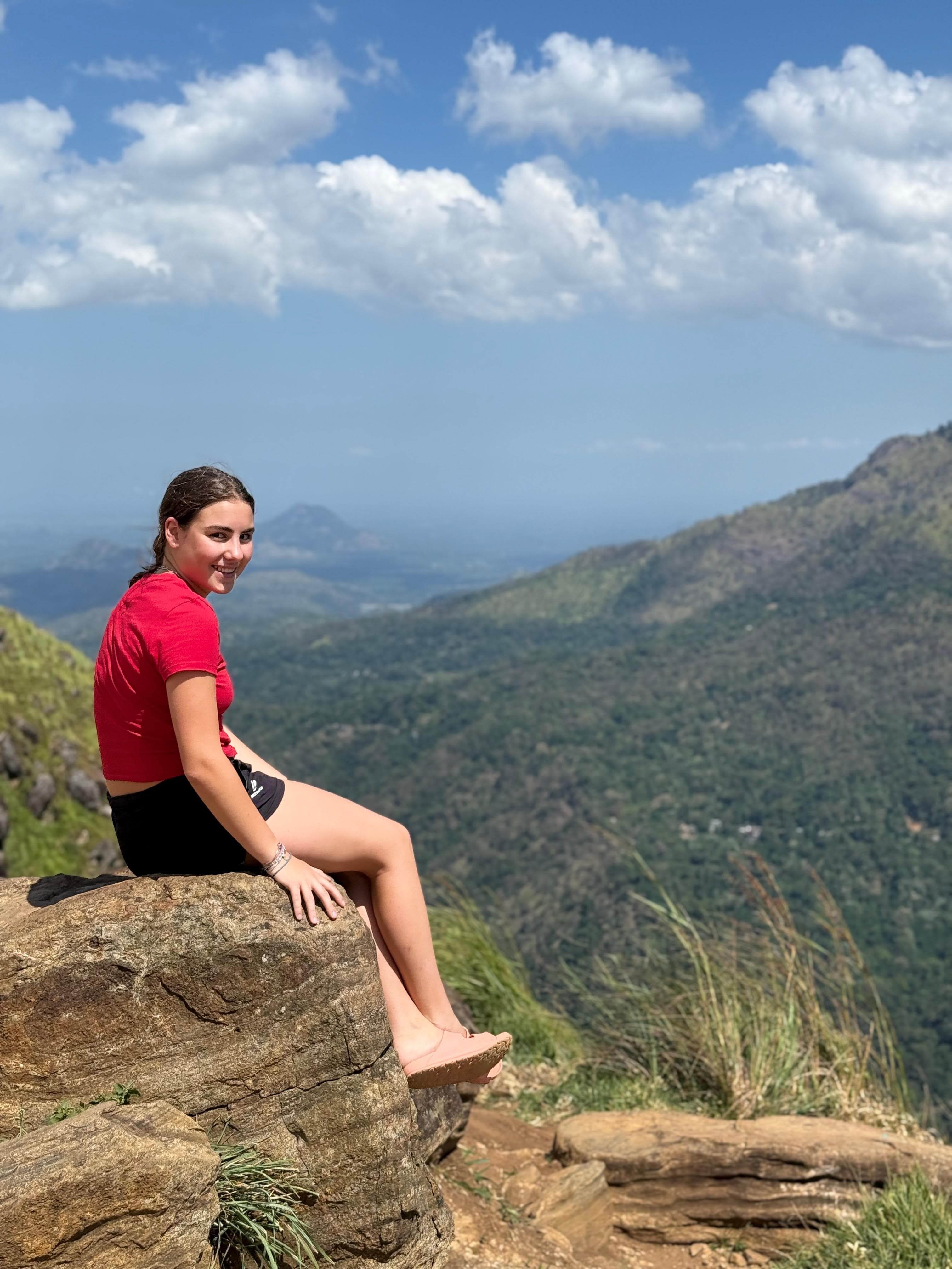 Woman on a rock ledge with a mountain panorama