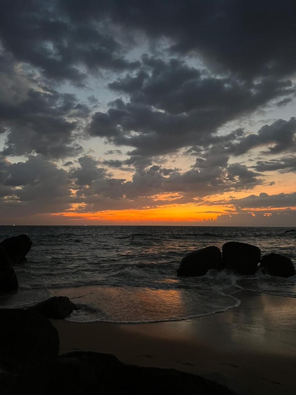 Dark sunset clouds over the beach rocks
