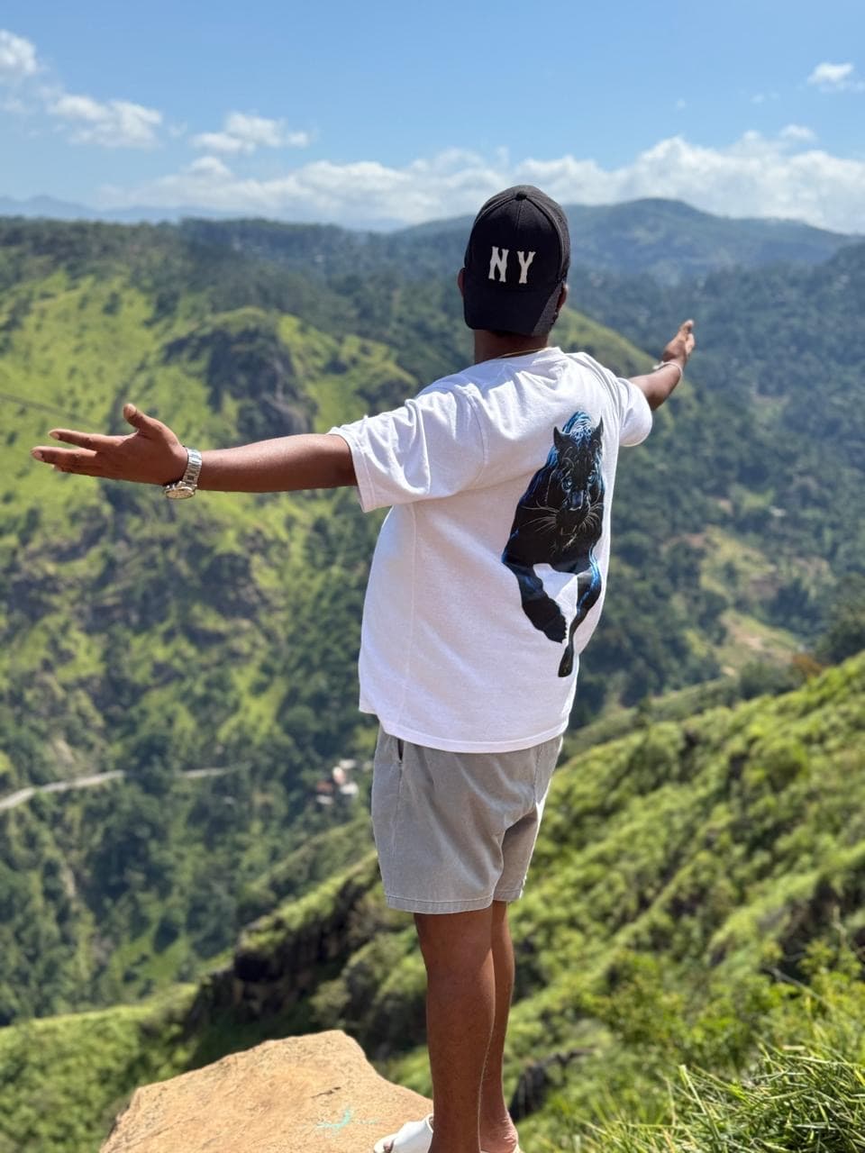 Man with arms open at a mountain viewpoint