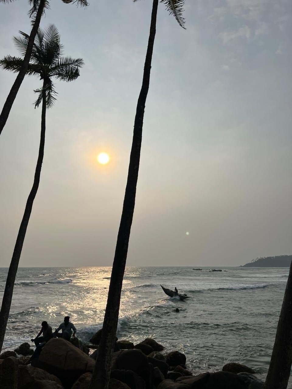 Palm trees and fishermen silhouetted at sunset