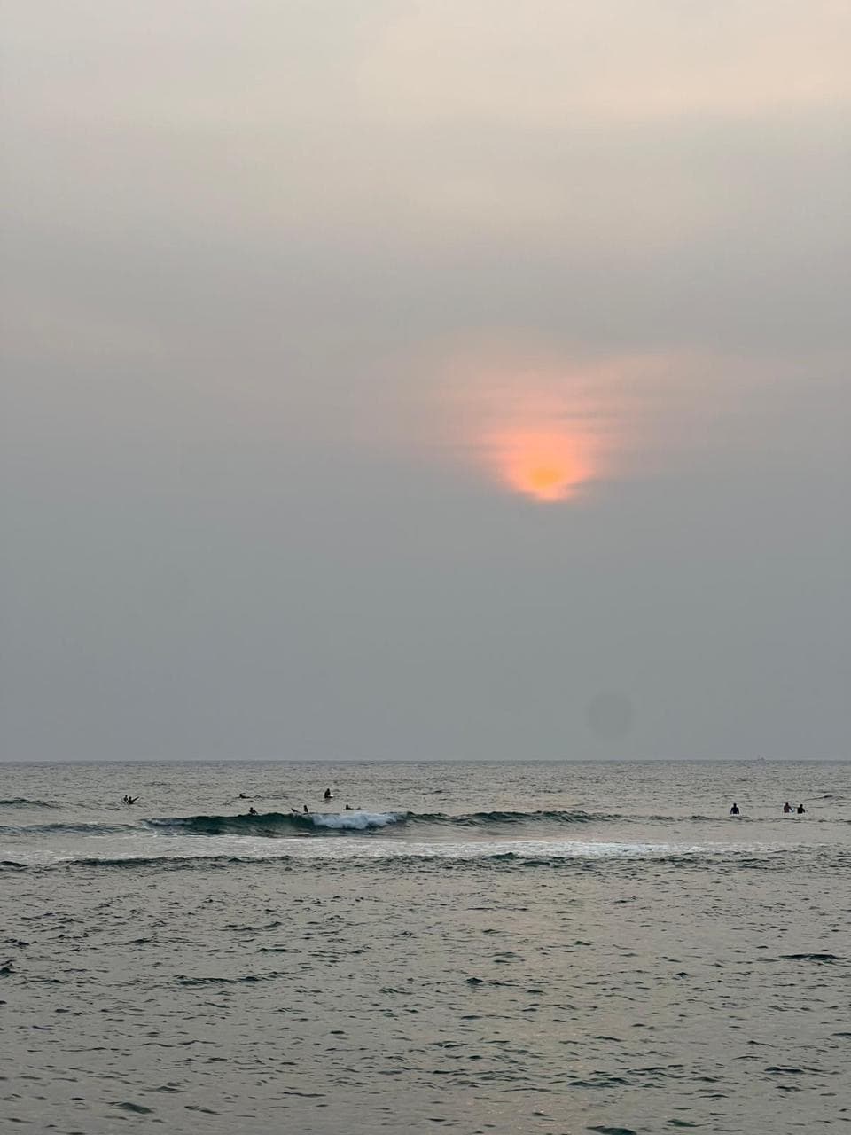 Surfers silhouetted against the ocean at sunset