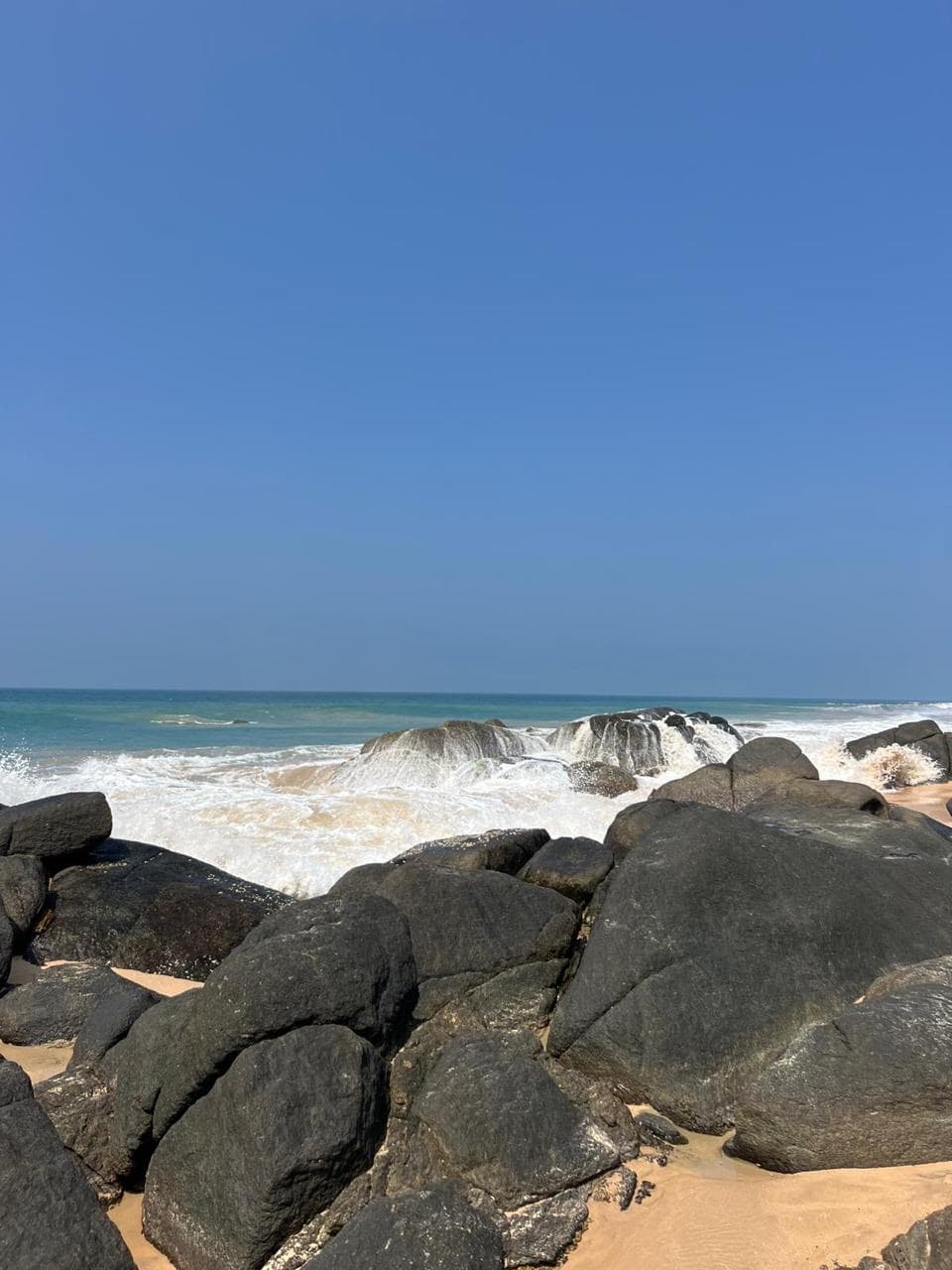 Waves crashing over boulders in a turquoise sea
