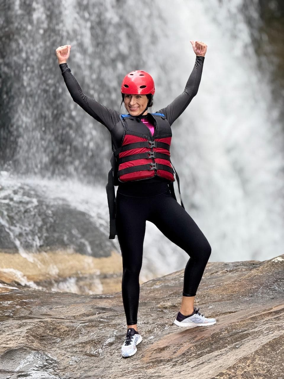 Woman celebrating during a canyoning waterfall adventure