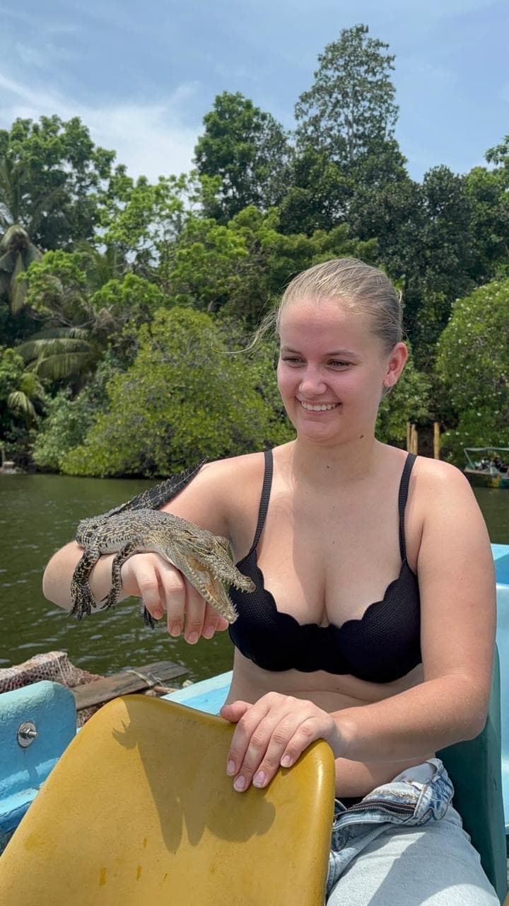 Woman holding a baby crocodile on a boat