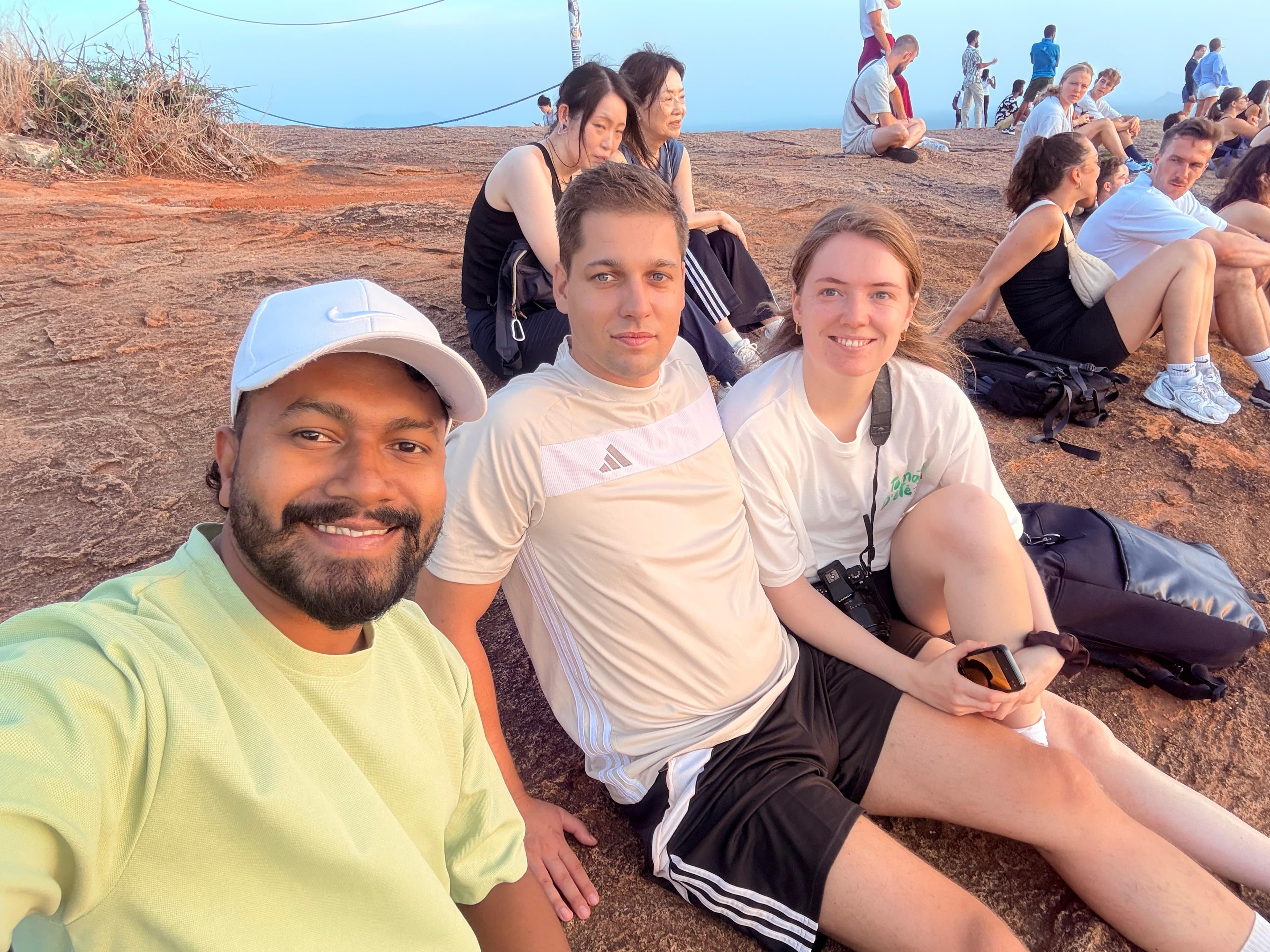 Chamara with guests at a rocky summit at sunset